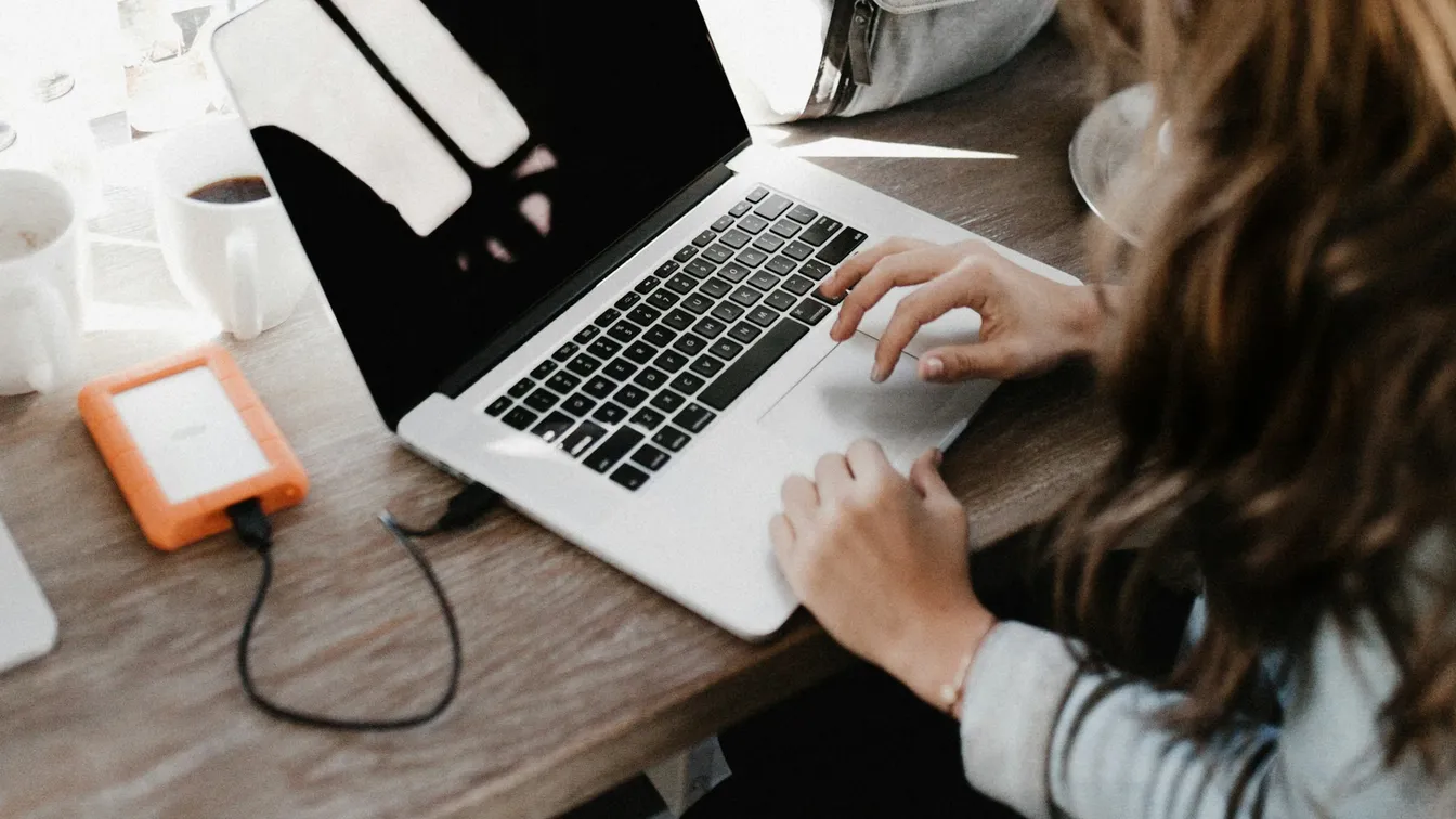 a woman using a laptop on a wooden table