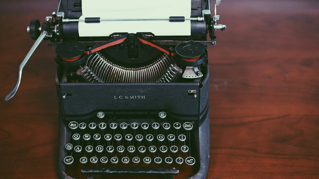 an old typewriter sits on a wooden table