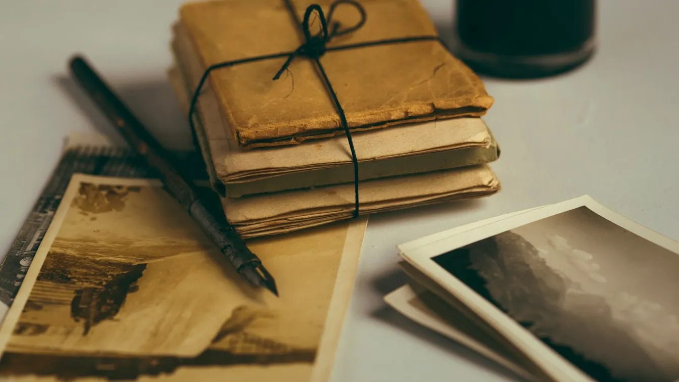 old books, photos and a pen on a table