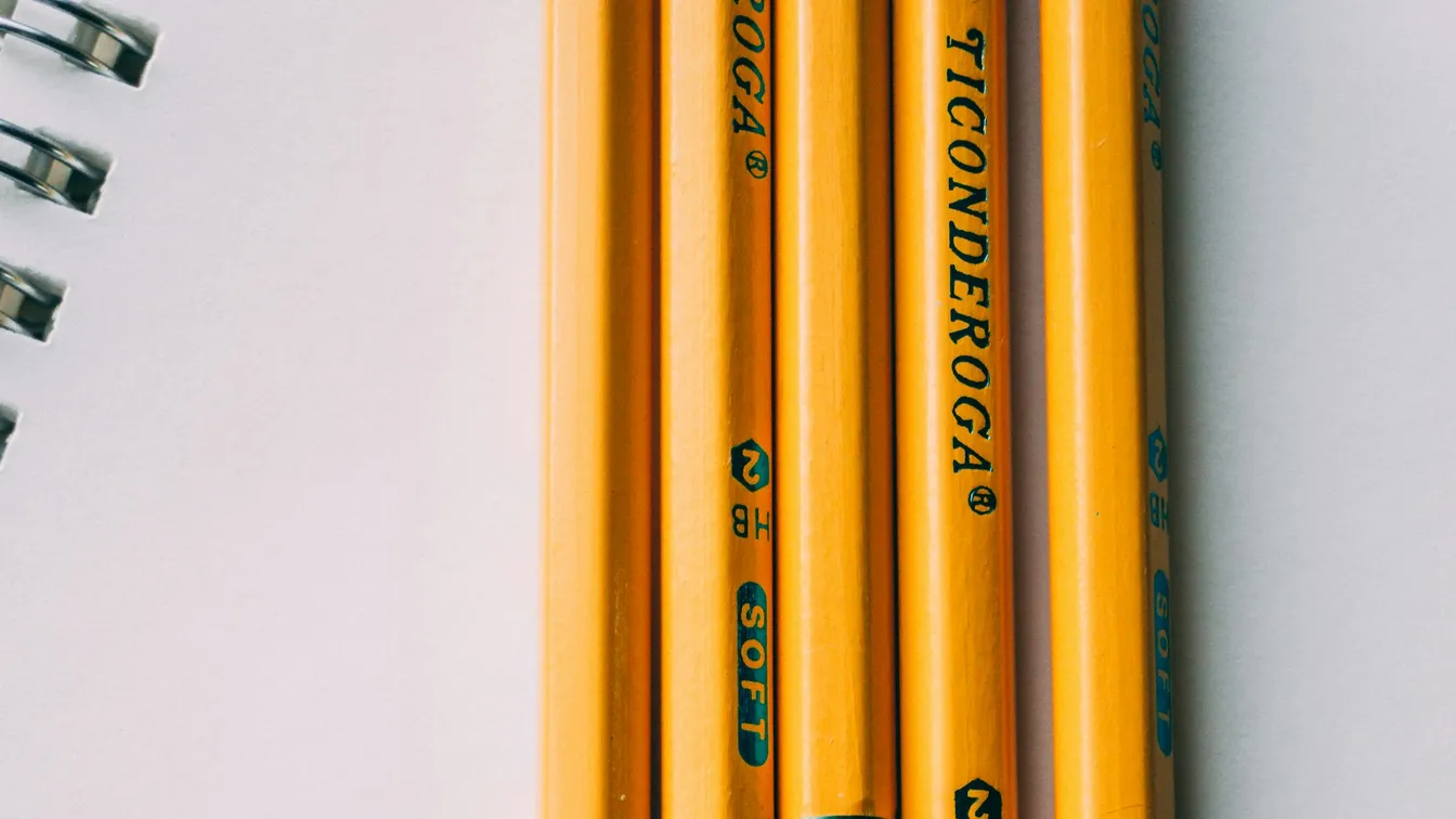 a group of yellow pencils next to a notebook