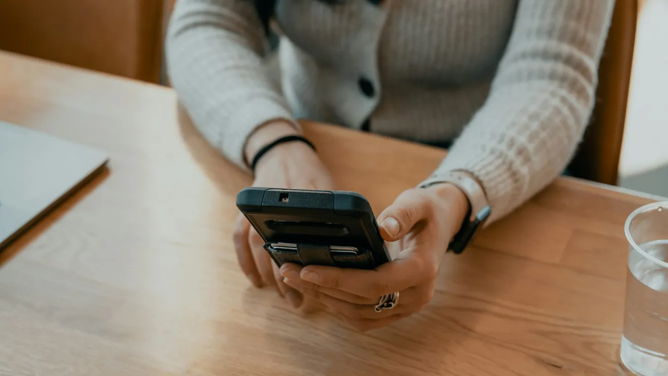 a woman holding a cell phone while sitting at a table