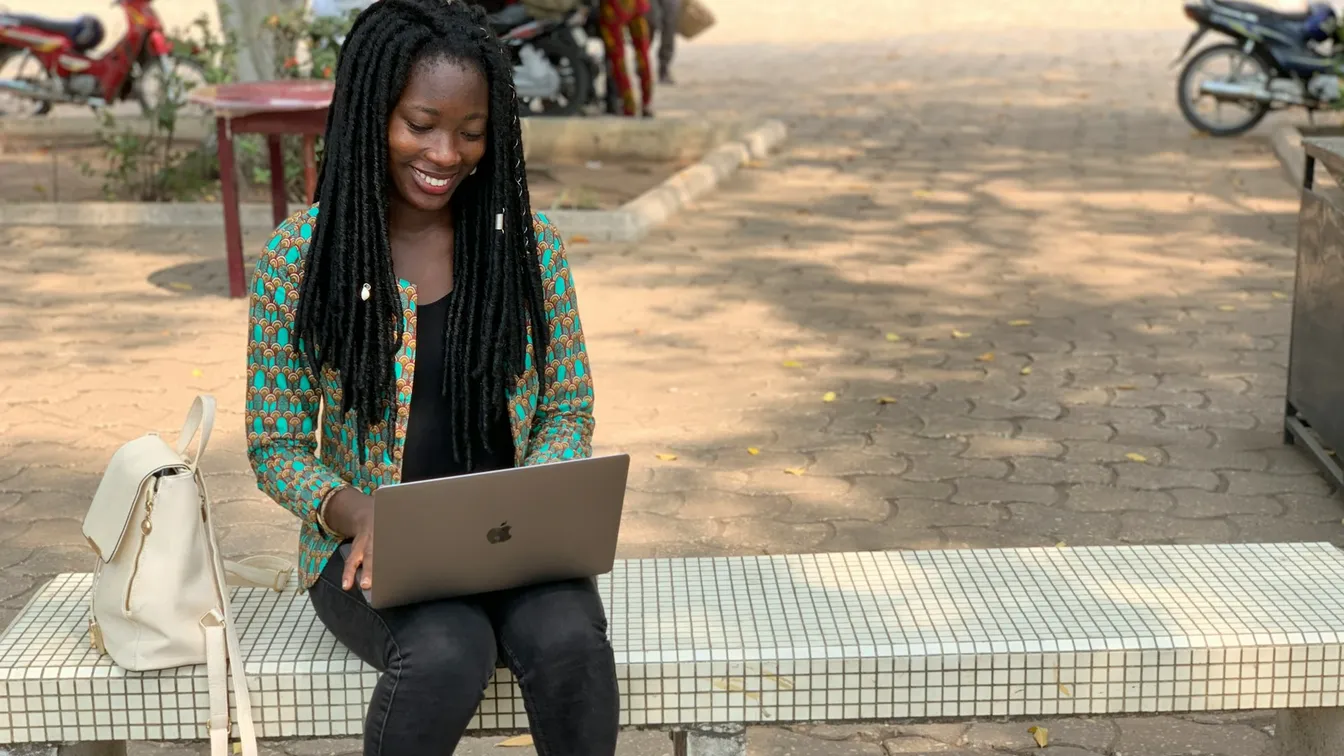 a young woman sitting on a bench with a laptop