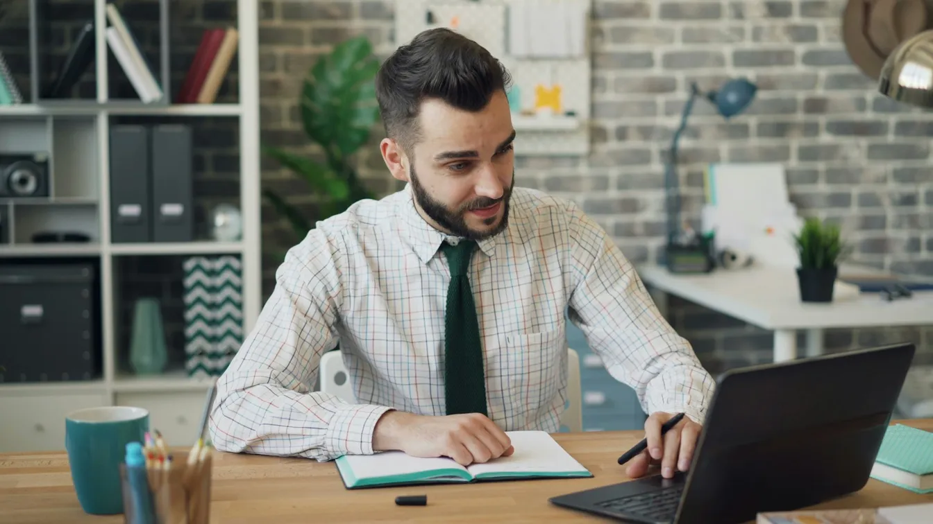 a man sitting at a desk with a laptop in front of him