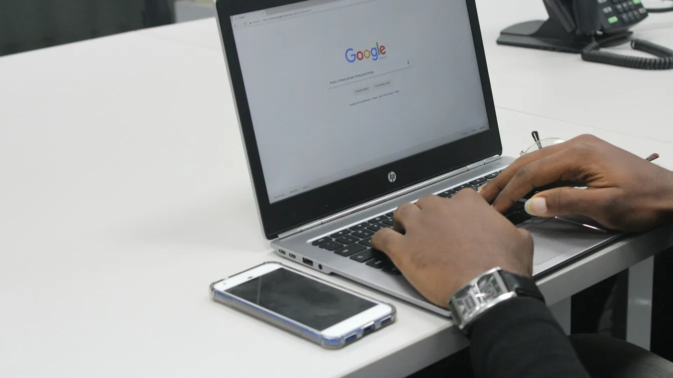 a man typing on a laptop with google on it