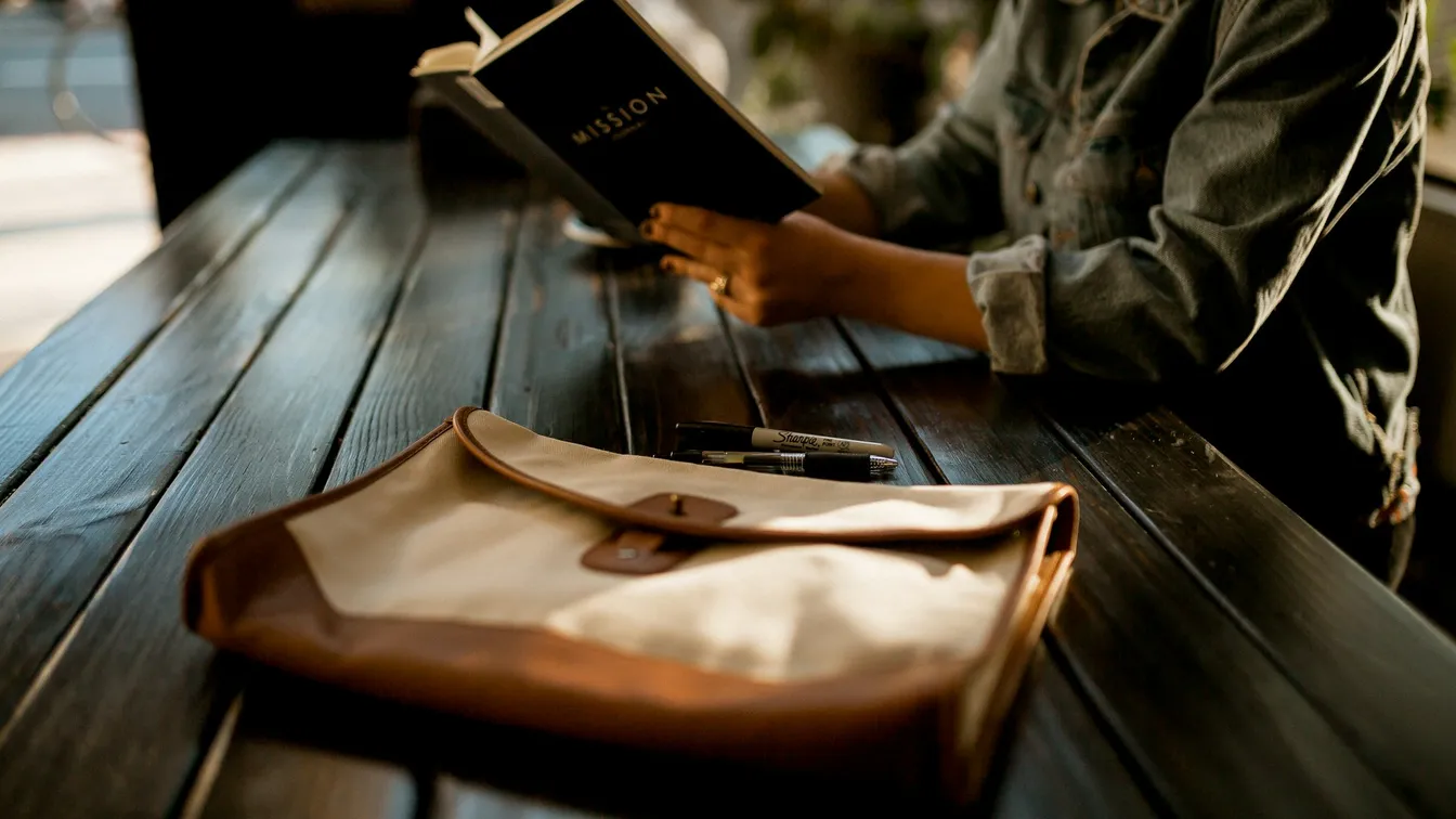 a woman is reading a book at a table