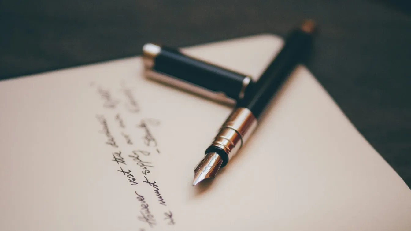 a fountain pen sits on top of a piece of paper