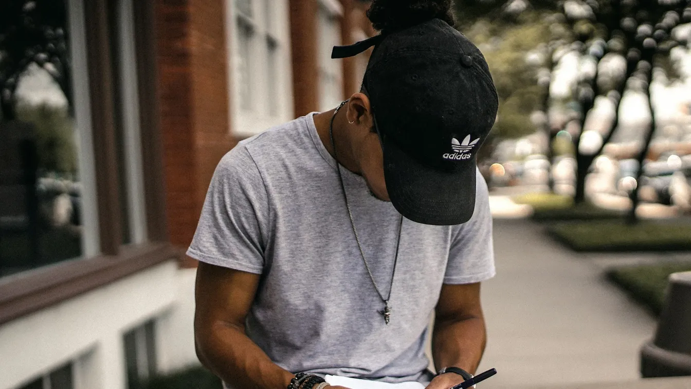 a man writing in a notebook on a sidewalk