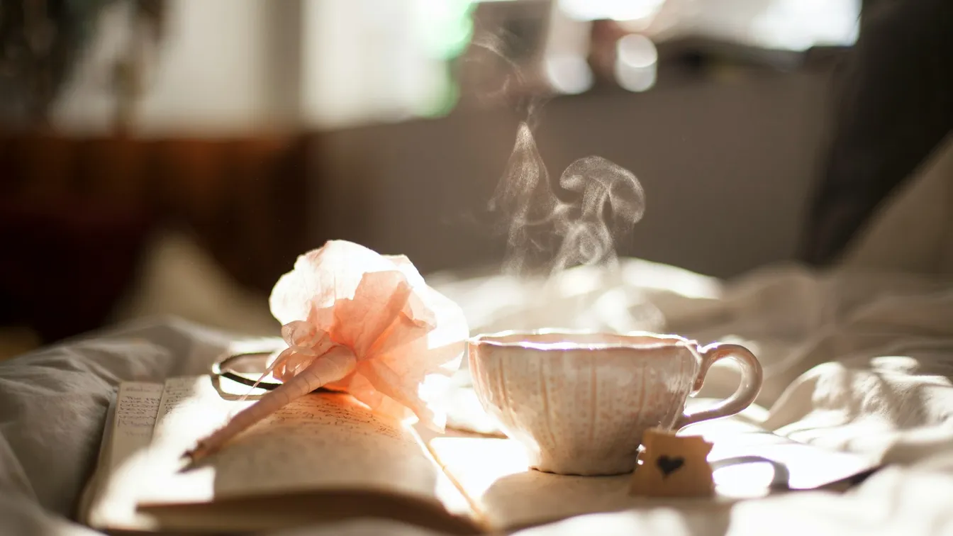 a cup of coffee and a book on a bed