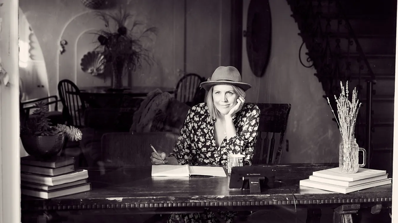 a woman in a hat sitting at a desk