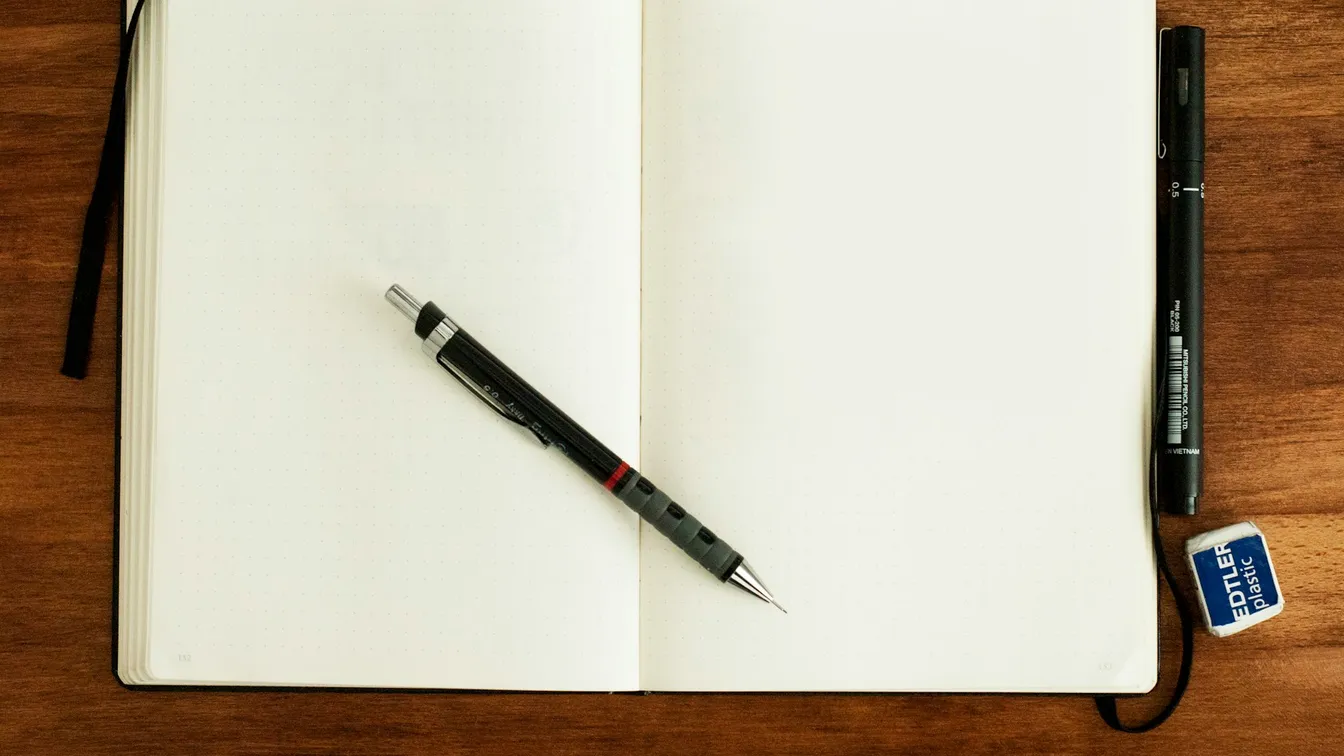 an open notebook with a pen on a wooden table